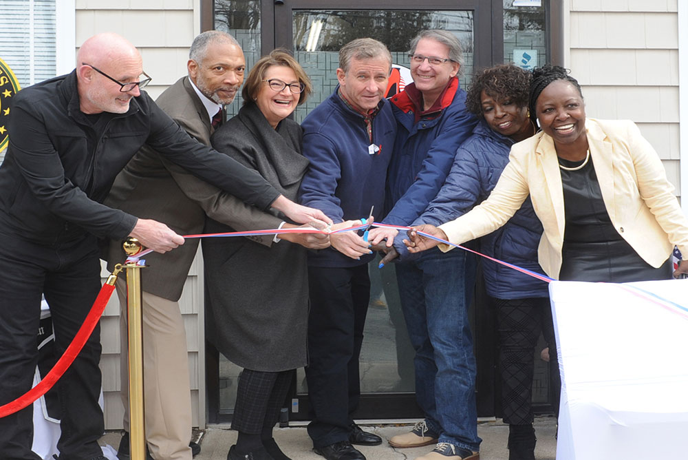 A group of people standing around each other holding a ribbon.